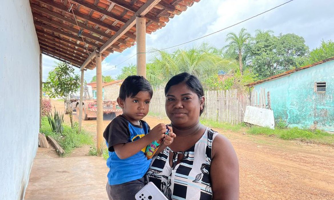 Imagem de uma mãe beneficiaria do Bolsa Família segurando o seu filho