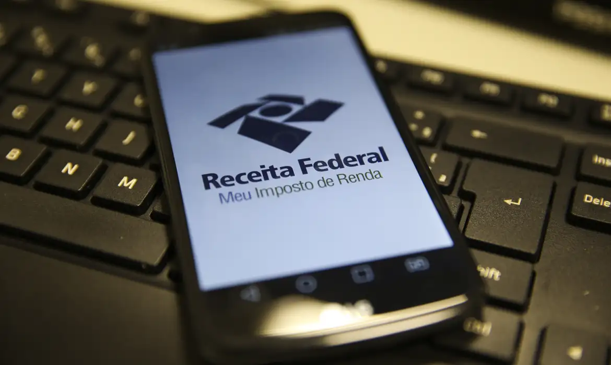 Celular com aplicativo da Receita Federal sobre teclado de computador