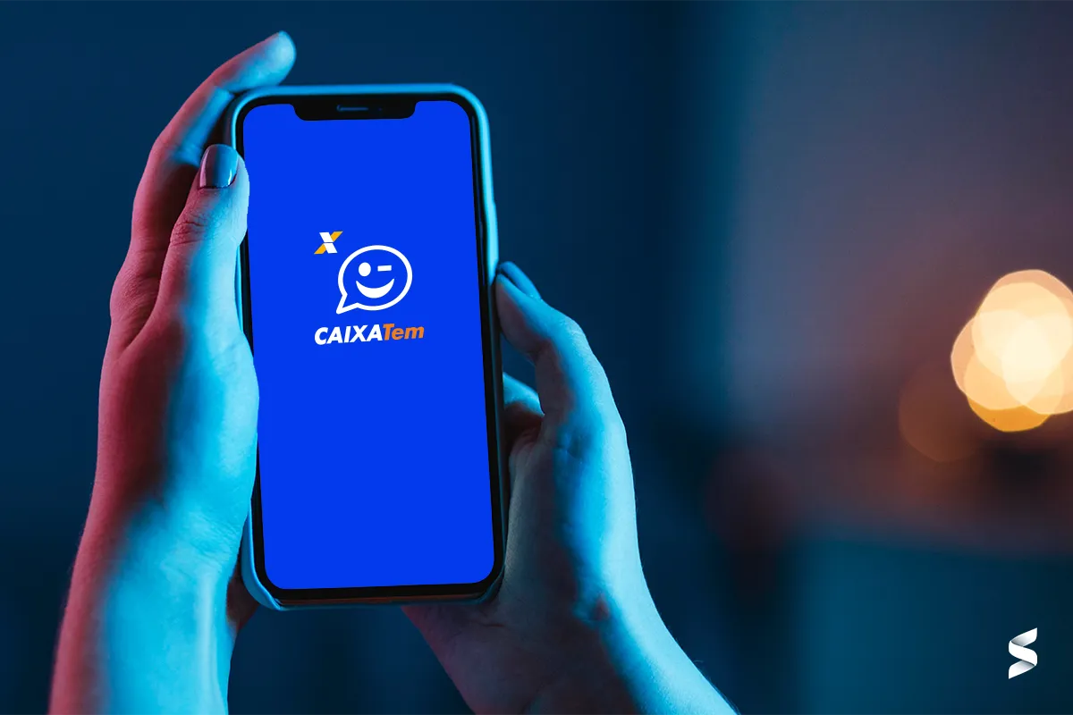 Usuário segurando smartphone com o layout do Caixa Tem, demonstrando o design mais limpo e organizado.